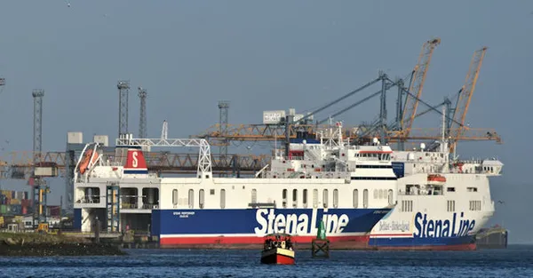 Two large white and blue Stena Line ferries moored at a port terminal with cranes behind.
