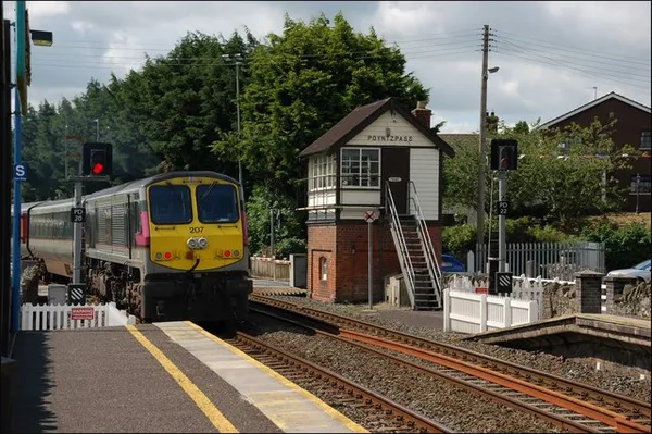 A passenger train at Poyntzpass station beside the brick and timber signal cabin.