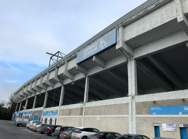 Beton tribüne des Semple Stadium mit dem Stadionschild und darunter geparkten Autos.