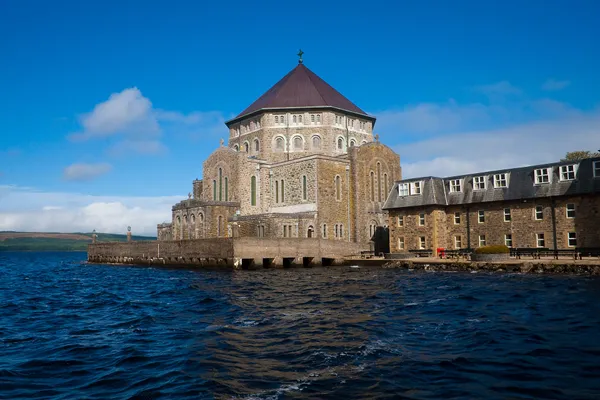 Una basilica in pietra con cupola ottagonale e un lungo edificio accanto, che si innalza dall'acqua.